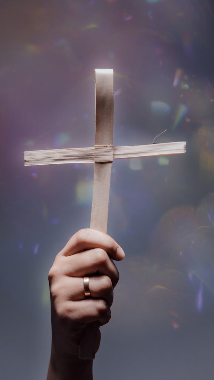 A hand holding a wooden cross with a ring, symbolizing faith and spirituality.