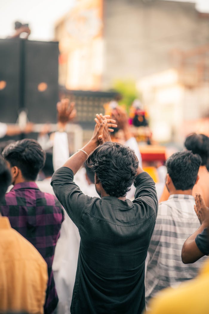 A group of people in an urban setting celebrate energetically with raised arms, creating a lively atmosphere.