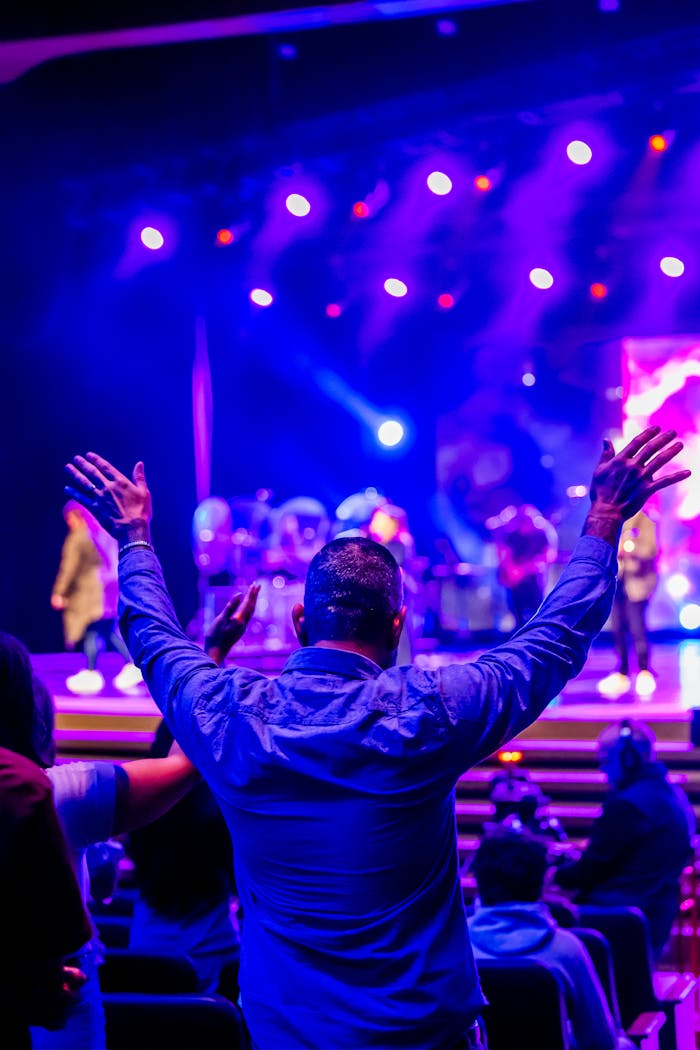 A person enjoying a live concert with vibrant stage lights.