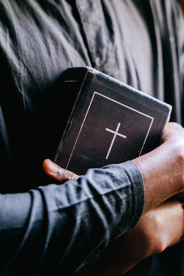 About Close-up of a person holding a holy bible with a cross, focusing on religion and faith.