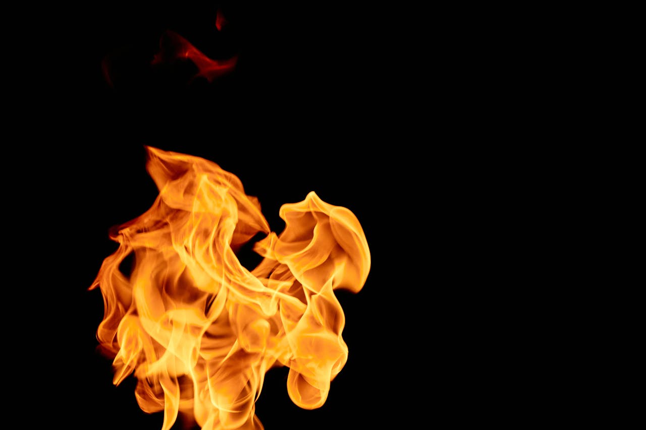 Close-up of vibrant flames isolated against a black backdrop, showcasing intricate shapes and textures.